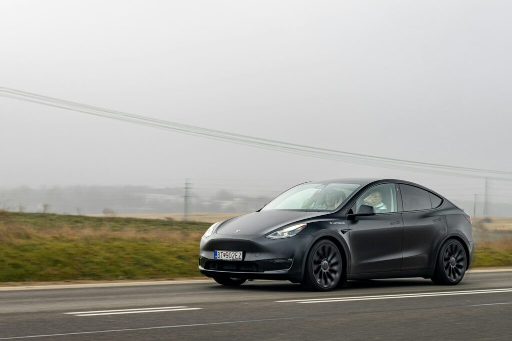 a black tesla car driving down the road